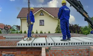 Pracownicy montują prefabrykowane płyty, które są jednym z rodzajów stropów. Budowa domu postępuje.